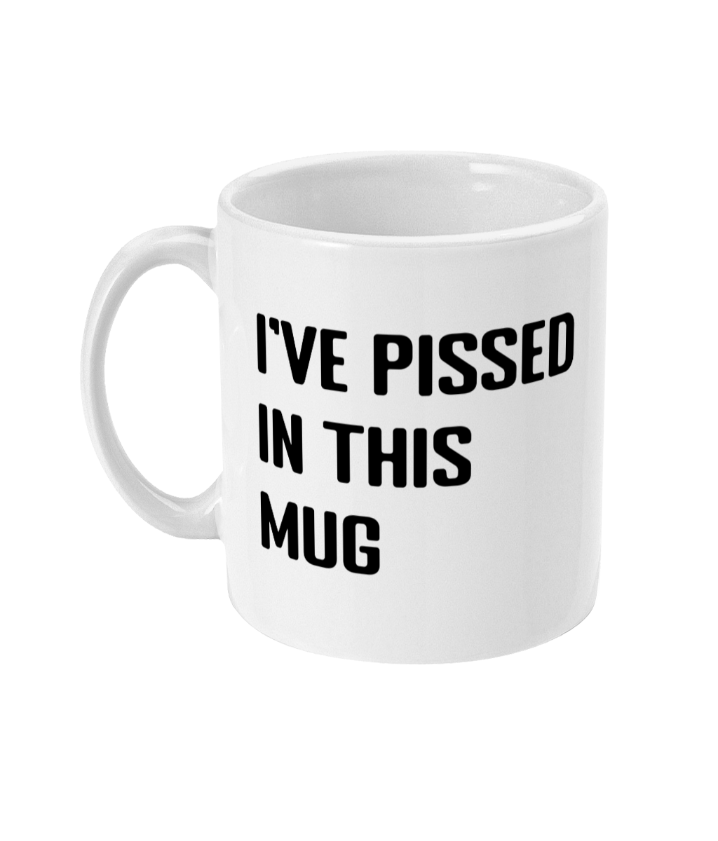 A glossy white 11oz mug with the words 'I've pissed in this mug' printed on it's centre in large block capital font. The mug is placed in front of a plain white background. 