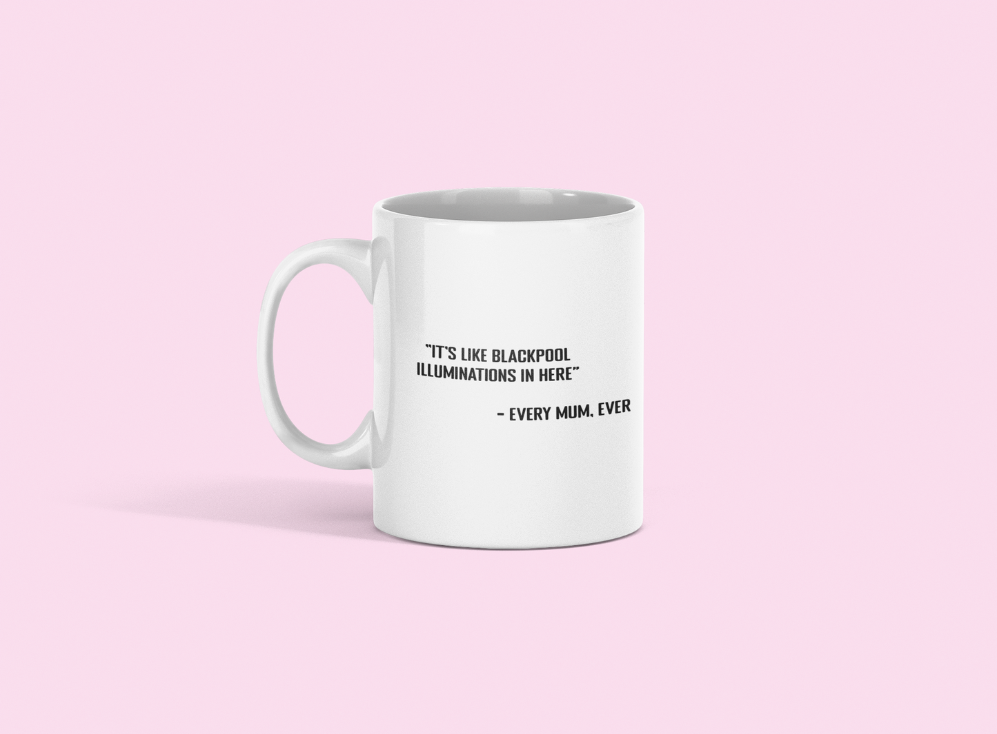 A glossy white 11oz mug with the statement 'it's like Blackpool illuminations in here - every mum, ever' printed on it's centre. The mug is placed against a pale pink background. 
