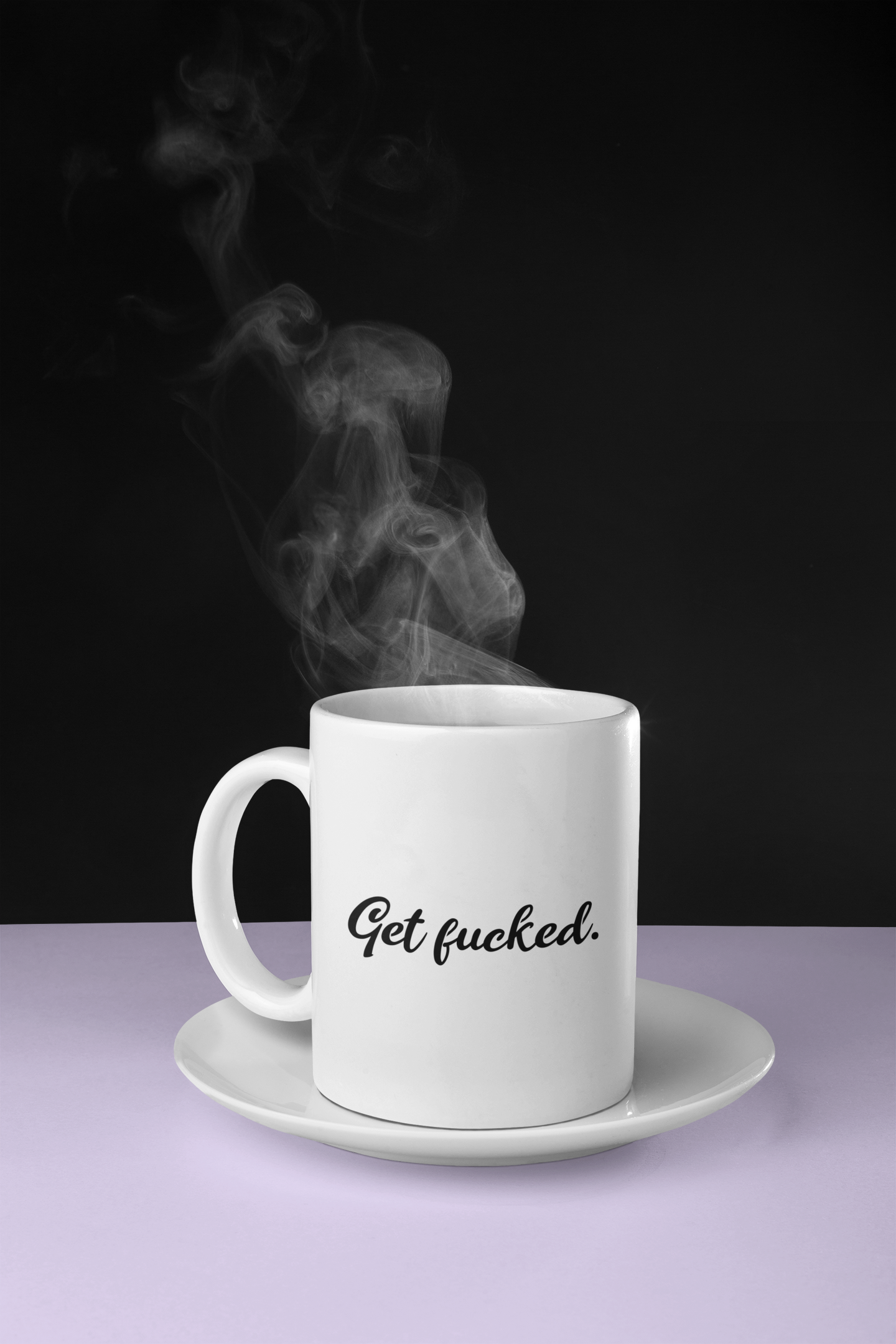 A simple 11oz glossy white mug with the words 'Get fucked.' printed in the centre in black cursive font. The mug is placed on a white saucer on a white table with a black background. Steam is coming out of the top of the mug. 